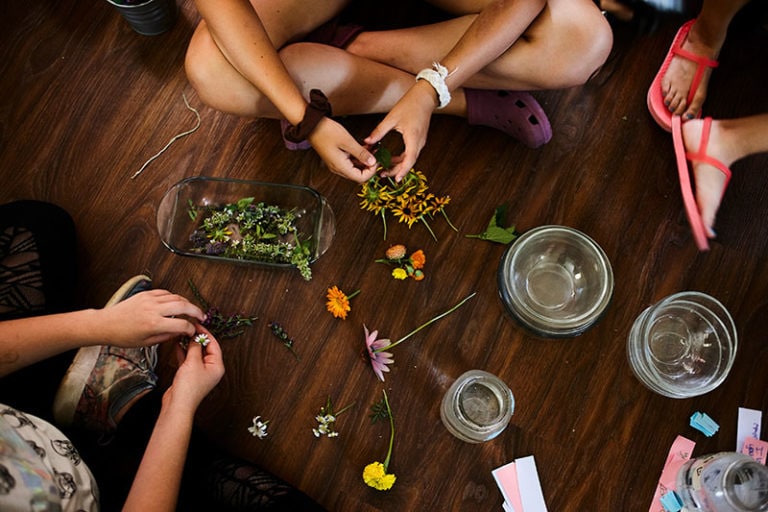 People sitting on the floor, preparing herbs and flowers for teas.