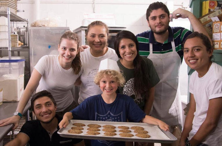 Group of seven people smiling with a child holding a tray of cookies.